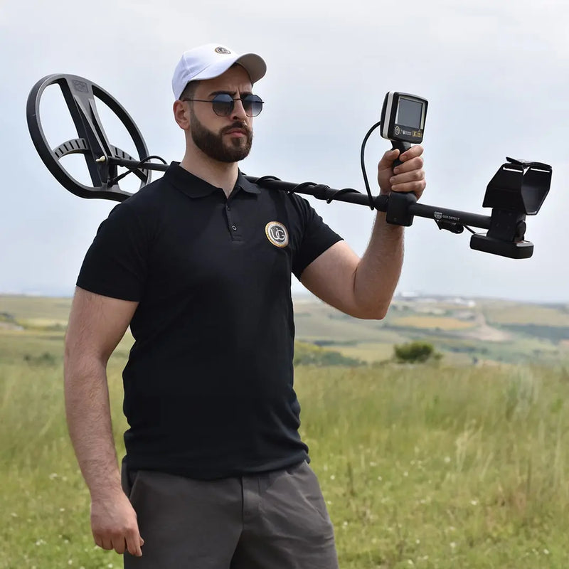 UIG Gold Digger device for detecting gold and precious metals, shown as a handheld metal detector in use.